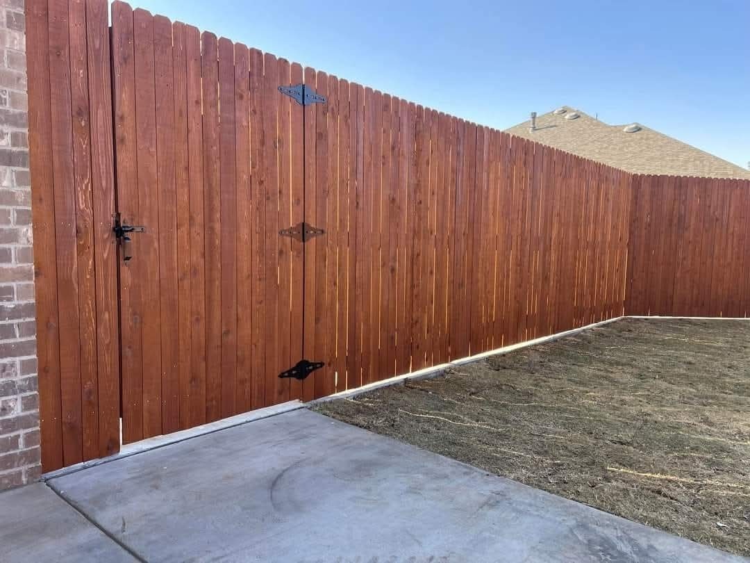 A stained wood gate and fence line along a brick home